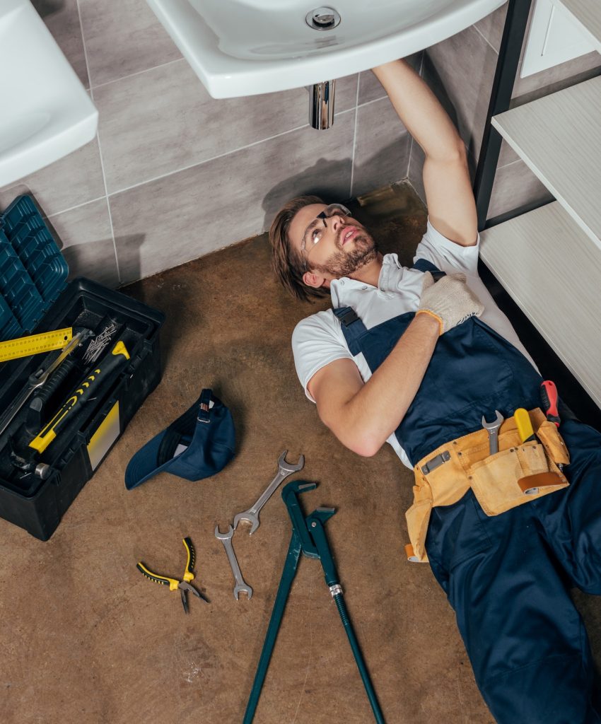 high-angle-view-of-young-male-plumber-fixing-sink-in-bathroom.jpg